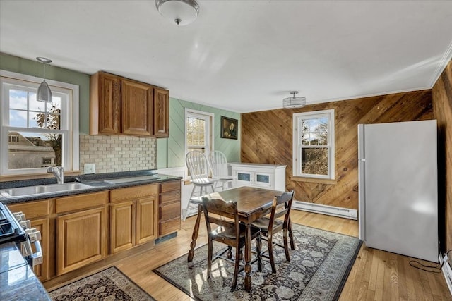 kitchen with sink, a baseboard radiator, white fridge, decorative light fixtures, and light wood-type flooring