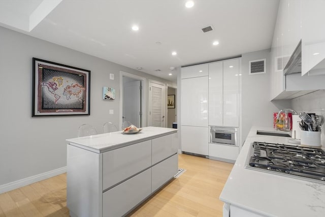133 Seaport Blvd Unit 716, Boston, MA 02210 - kitchen featuring modern cabinets, stainless steel appliances, white cabinetry, light countertops, and light wood-style flooring