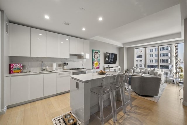 133 Seaport Blvd Unit 716, Boston, MA 02210 - kitchen with a sink, gas stovetop, white cabinets, light wood-style flooring, and light countertops