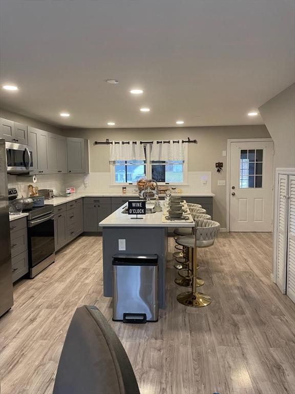 kitchen featuring gray cabinetry, a kitchen island, light wood-type flooring, and appliances with stainless steel finishes