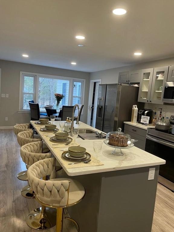 kitchen featuring gray cabinets, appliances with stainless steel finishes, sink, a kitchen bar, and light wood-type flooring