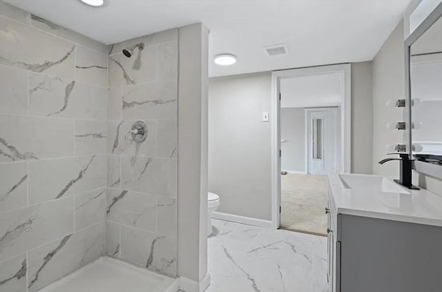 bathroom featuring vanity, toilet, and tiled shower