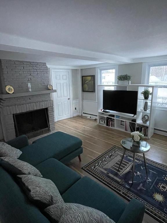 living room with hardwood / wood-style floors, a brick fireplace, and a baseboard heating unit