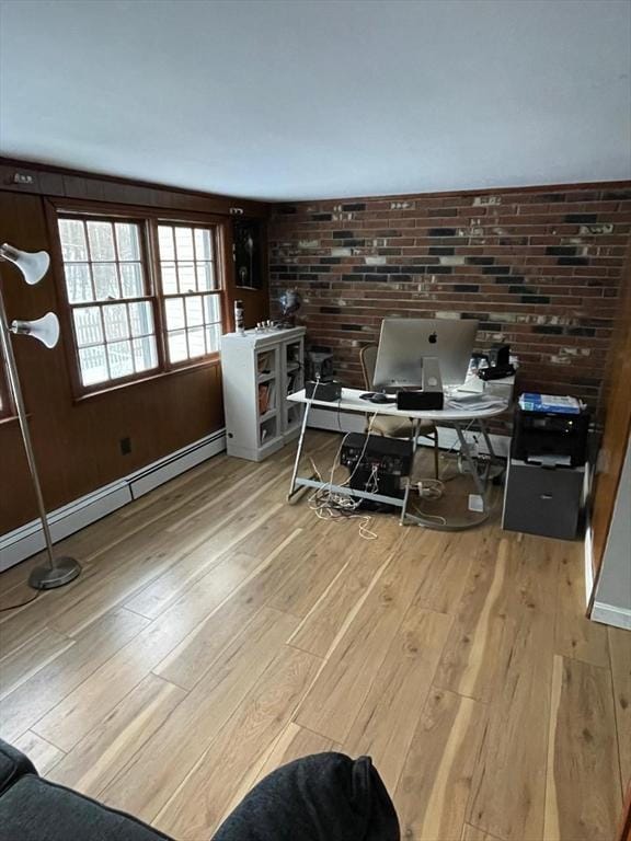 office space with a baseboard radiator, light hardwood / wood-style floors, and brick wall