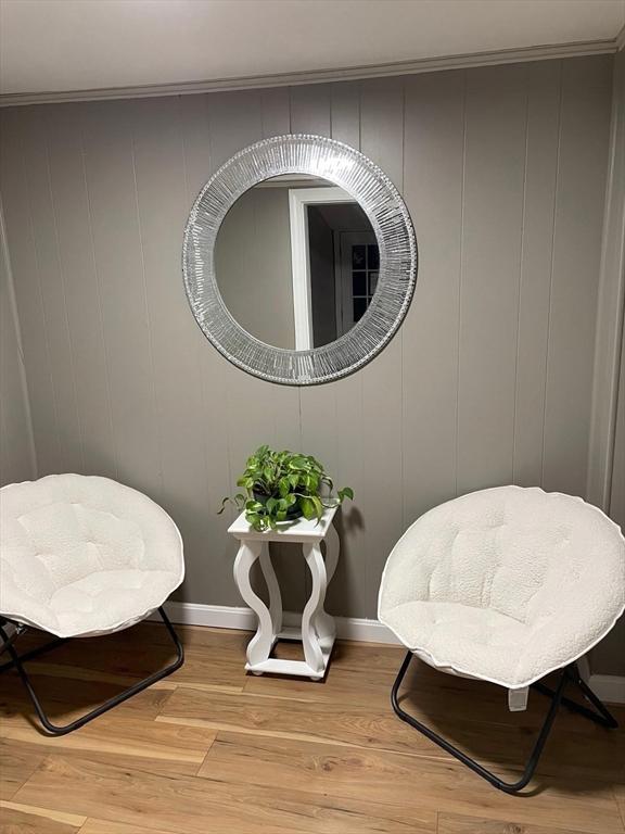 sitting room with crown molding and light hardwood / wood-style floors