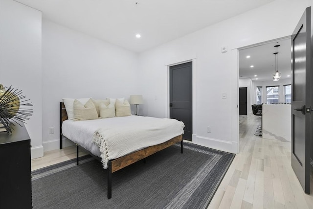 bedroom with baseboards, light wood-type flooring, and recessed lighting