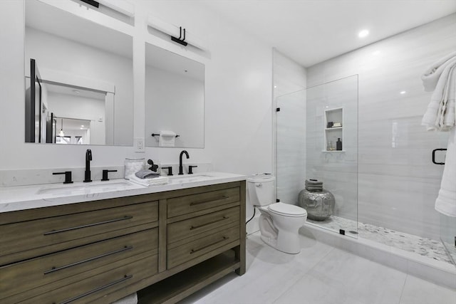 bathroom featuring toilet, a shower stall, double vanity, and a sink