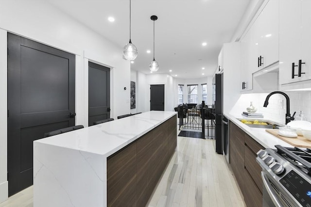 kitchen featuring a sink, white cabinetry, a center island, modern cabinets, and stainless steel range with gas stovetop