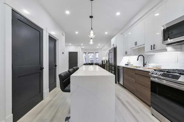 kitchen with appliances with stainless steel finishes, modern cabinets, a sink, and white cabinetry