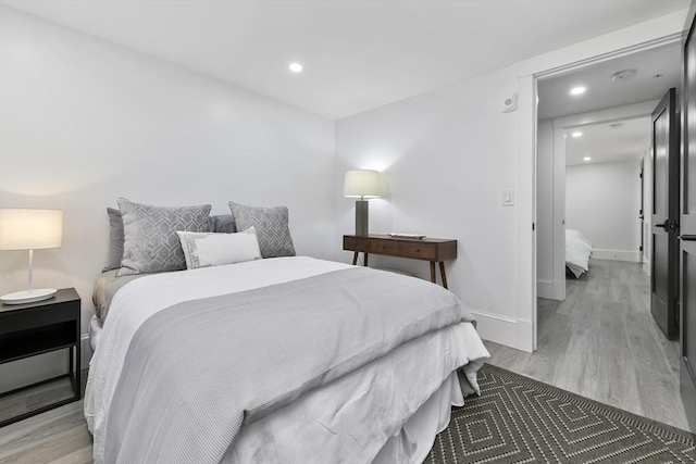 bedroom with light wood-style floors, baseboards, and recessed lighting