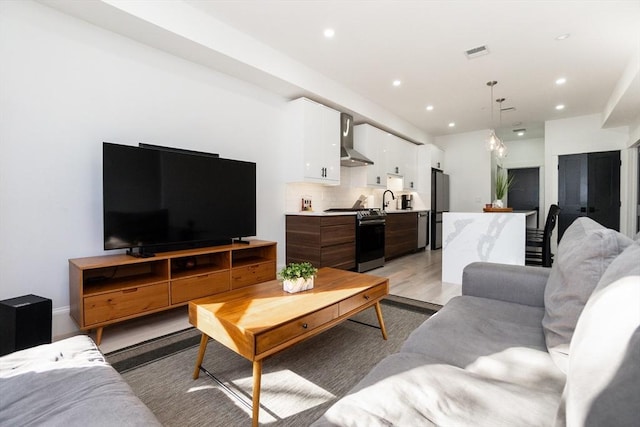 living area with light wood-style floors, visible vents, and recessed lighting