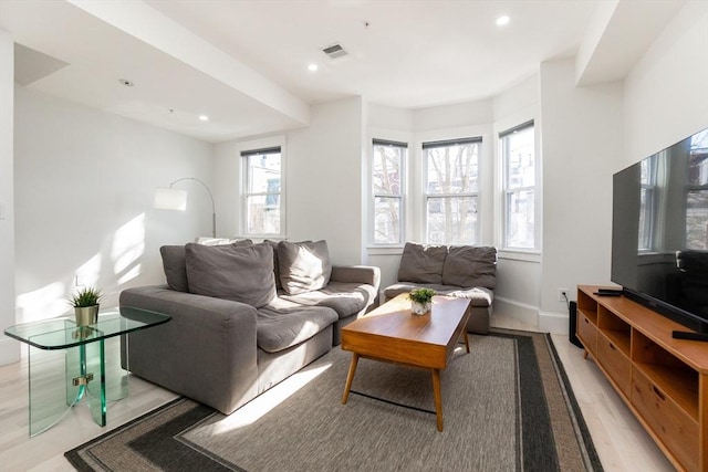 living area with light wood-style floors, visible vents, baseboards, and recessed lighting