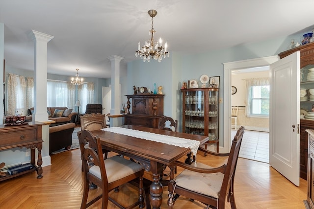 dining area with a chandelier, decorative columns, and light parquet flooring