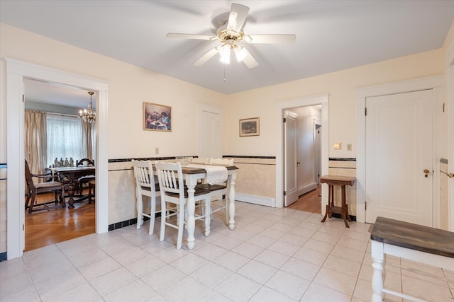 tiled dining room featuring ceiling fan with notable chandelier