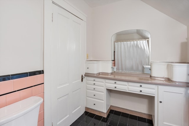 bathroom with tile patterned flooring, tile walls, toilet, and vanity