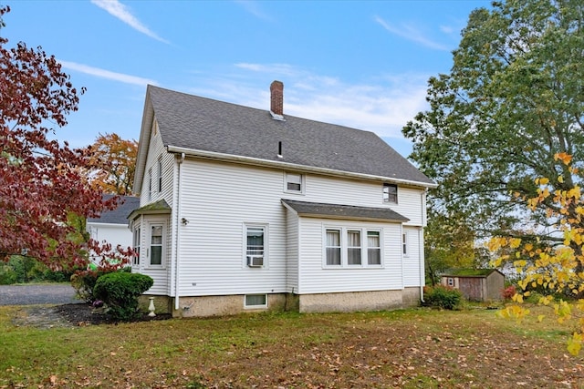 back of house featuring a yard and a storage unit