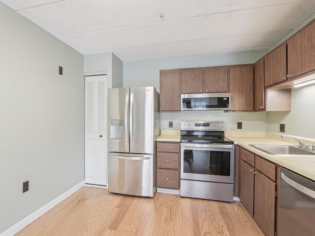 881 Broadway Unit 16, Everett, MA 02149 - kitchen with stainless steel appliances, light wood-type flooring, light countertops, and brown cabinets