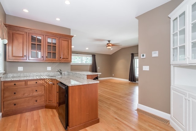 kitchen featuring kitchen peninsula, light stone counters, sink, dishwasher, and light hardwood / wood-style floors