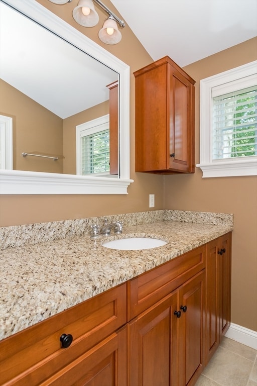 bathroom with tile patterned flooring, vanity, and vaulted ceiling