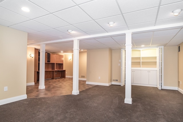 basement featuring a paneled ceiling and dark colored carpet