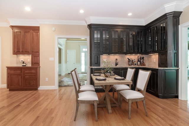 bar featuring tasteful backsplash, dark brown cabinetry, light hardwood / wood-style flooring, and ornamental molding