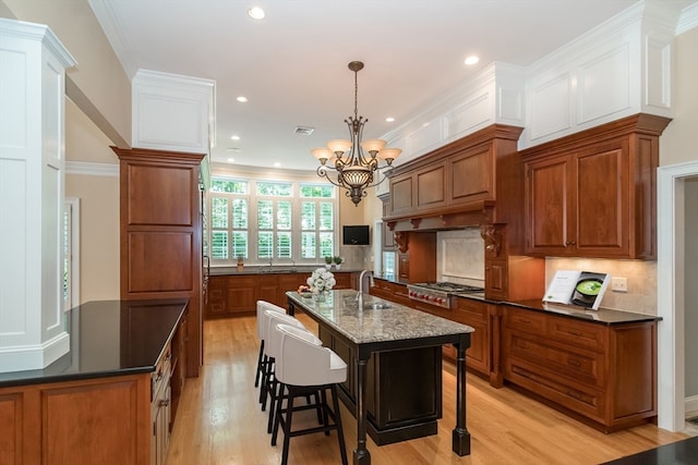 kitchen featuring hanging light fixtures, tasteful backsplash, an island with sink, stainless steel gas stovetop, and a breakfast bar area