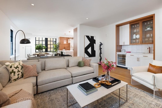 living room featuring wine cooler, light hardwood / wood-style flooring, and indoor wet bar