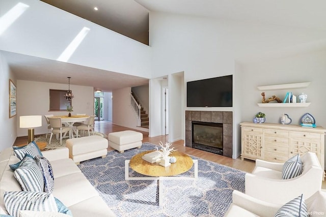 living room featuring an inviting chandelier, a fireplace, high vaulted ceiling, and light hardwood / wood-style floors