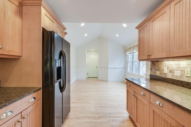 kitchen with tasteful backsplash, lofted ceiling, dark stone countertops, and black refrigerator with ice dispenser