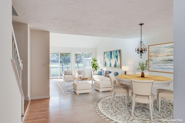 dining room featuring vaulted ceiling, an inviting chandelier, and light hardwood / wood-style floors