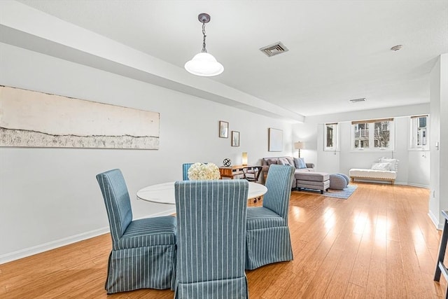 dining space featuring visible vents, light wood-style flooring, and baseboards