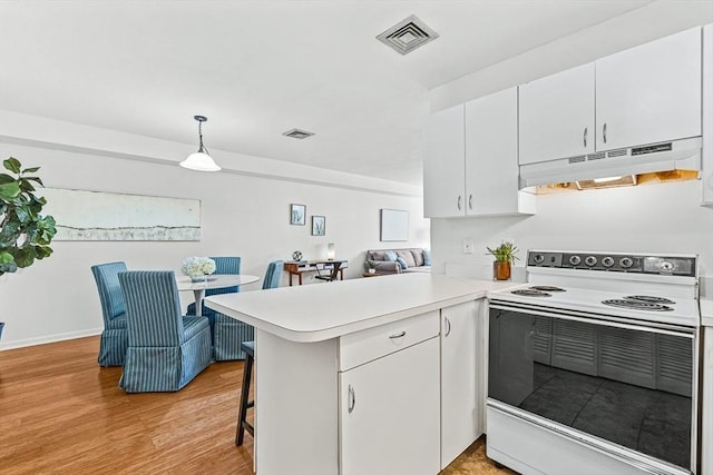 kitchen with under cabinet range hood, a peninsula, visible vents, light countertops, and white range with electric cooktop