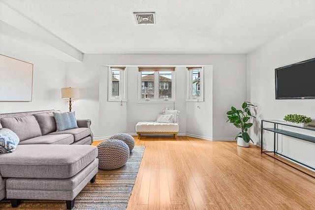 living area with a textured ceiling, hardwood / wood-style flooring, and baseboards