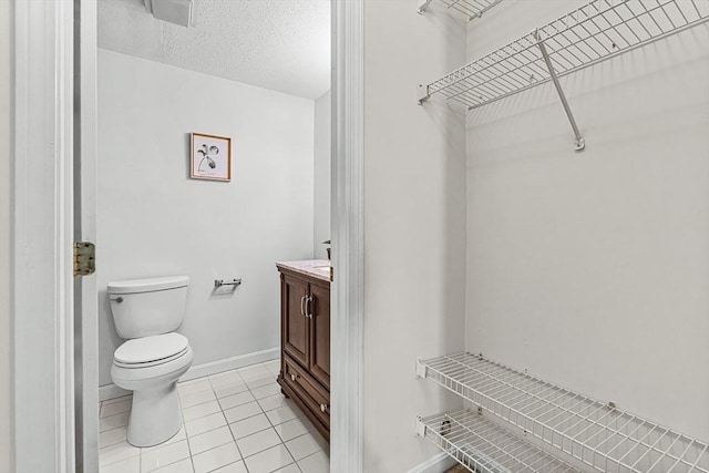 bathroom with toilet, a textured ceiling, vanity, tile patterned flooring, and baseboards