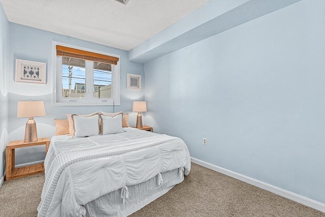 carpeted bedroom with a textured ceiling and baseboards