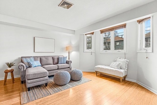 living room featuring a wealth of natural light, visible vents, and light wood-style flooring