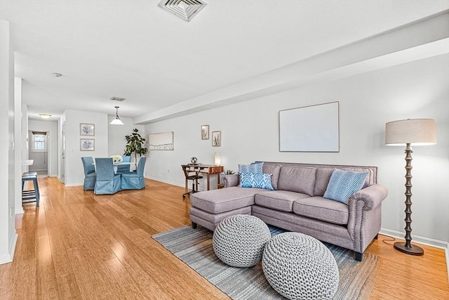 living room featuring light wood finished floors, baseboards, and visible vents