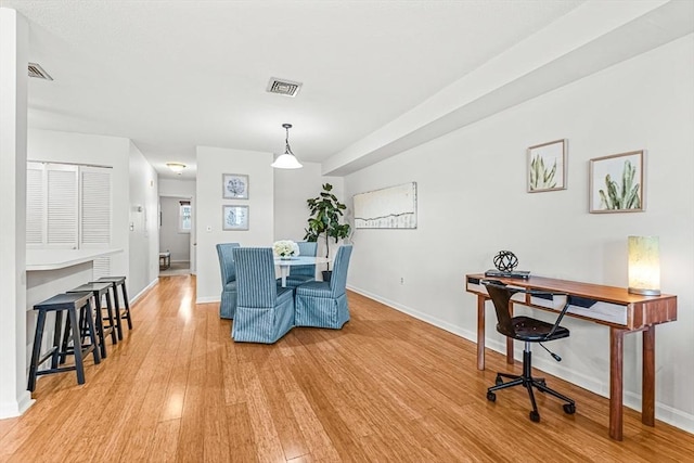 dining space featuring light wood-style floors, visible vents, and baseboards