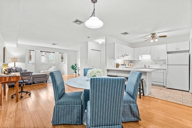 dining area featuring light wood-type flooring, visible vents, and ceiling fan