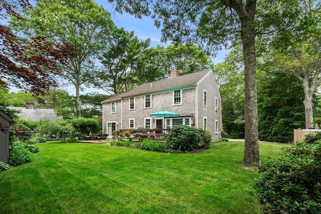 rear view of house featuring a deck and a lawn