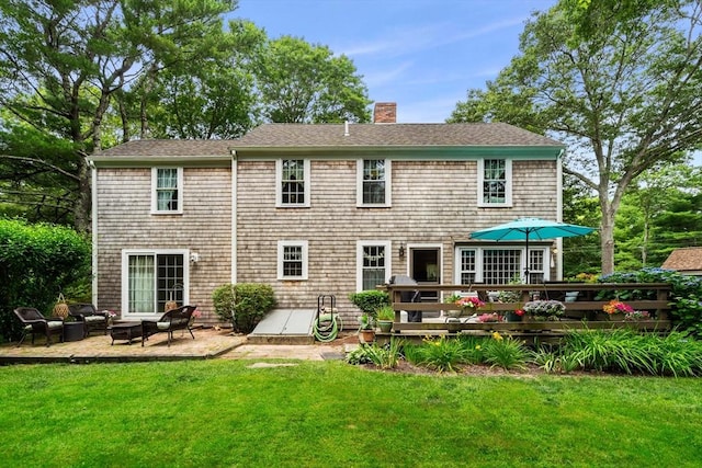 rear view of property featuring a lawn, a wooden deck, and a patio area