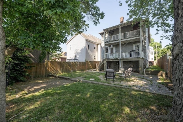 23 Essex St, Revere, MA 02151 - rear view of house with a fenced backyard, a chimney, a patio area, a balcony, and an outdoor fire pit