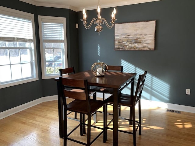 dining room featuring crown molding, a notable chandelier, and light wood-type flooring