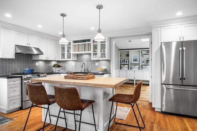 42 Pickwick Rd, Marblehead, MA 01945 - kitchen featuring stainless steel appliances, under cabinet range hood, butcher block counters, a kitchen breakfast bar, and glass insert cabinets