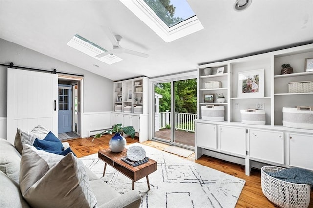 42 Pickwick Rd, Marblehead, MA 01945 - living area featuring vaulted ceiling, a ceiling fan, a skylight, light wood-type flooring, and a barn door