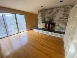 unfurnished living room with a large fireplace and wood finished floors