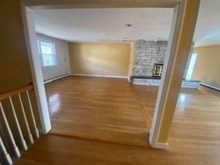 unfurnished living room with baseboards, wood finished floors, and a fireplace