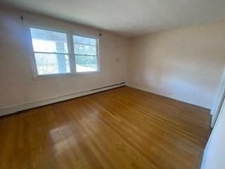 empty room featuring a baseboard radiator and wood finished floors