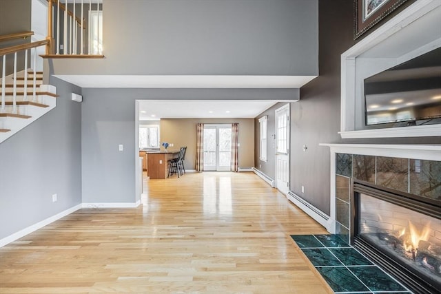 105 Edgewater Dr W, Falmouth, MA 02536 - unfurnished living room featuring stairway, light wood finished floors, baseboards, a tiled fireplace, and baseboard heating