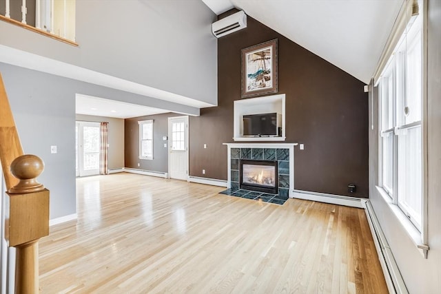 105 Edgewater Dr W, Falmouth, MA 02536 - unfurnished living room with a baseboard heating unit, light wood-style floors, a tiled fireplace, and high vaulted ceiling